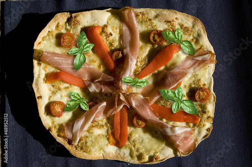 Pizza with tomatoes, pepper, ham and basil top view