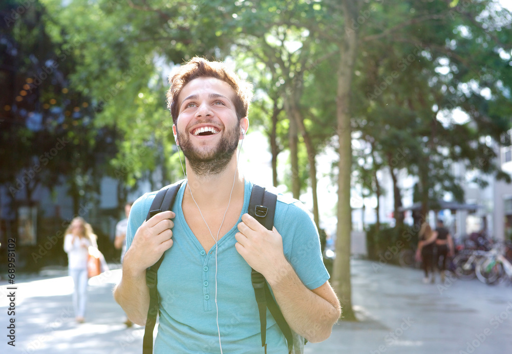 Fototapeta premium Portrait of a handsome young man walking outdoors with backpack