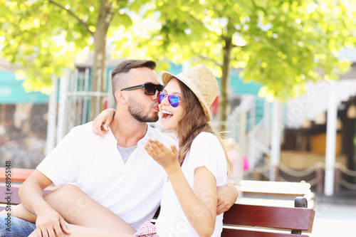 Joyful couple kissing on a bench © Kalim