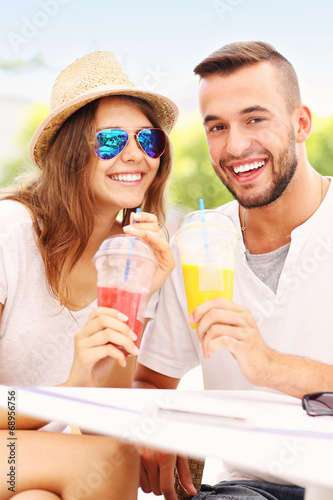 Joyful couple and smoothies in a cafe