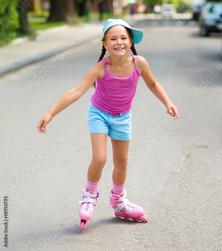 Happy little girl is skating on rollers