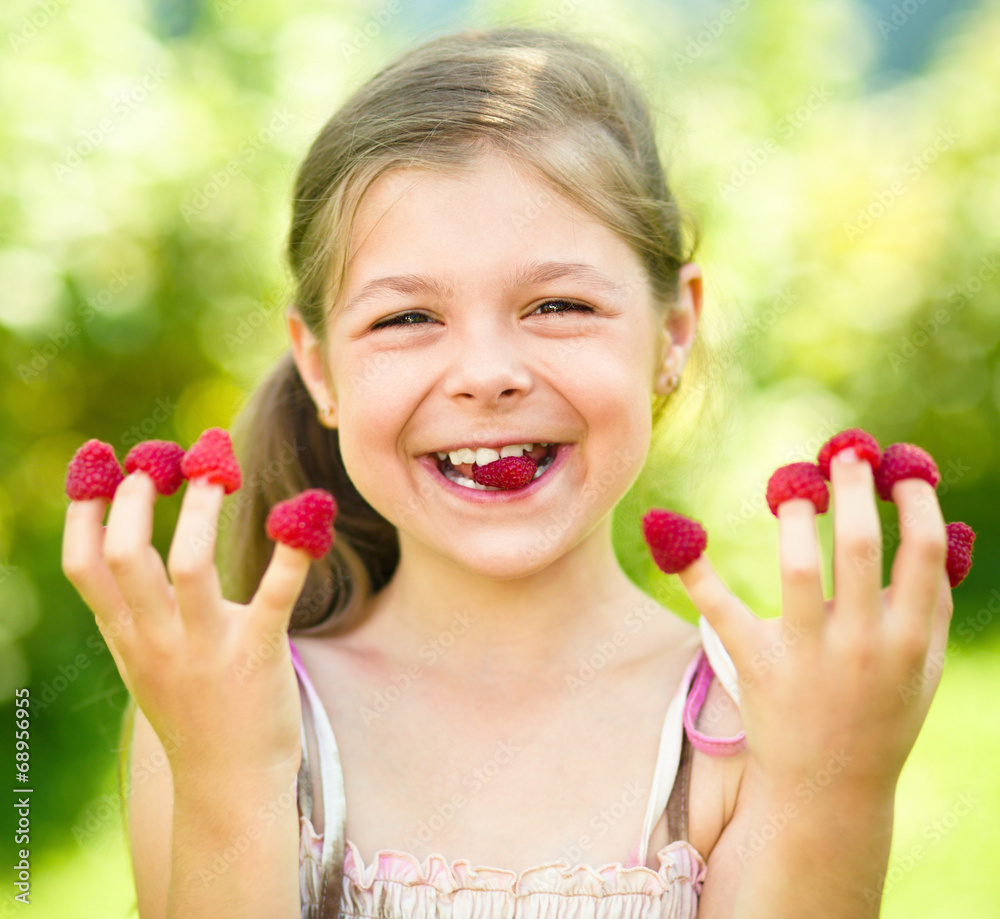 Young girl is holding raspberries on her fingers Young girl is holding raspberries on her fingers
