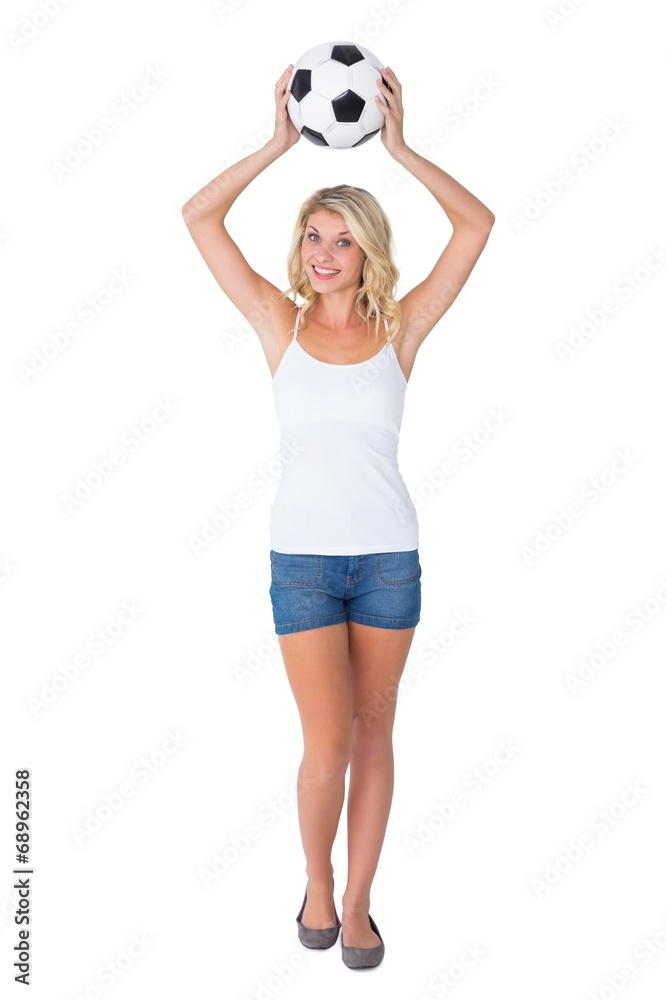 Pretty football fan holding ball over head Pretty football fan holding ball over head