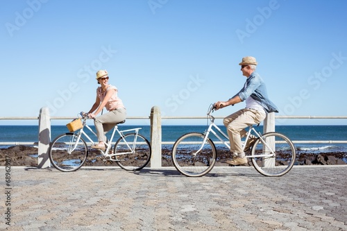 Happy casual couple going for a bike ride on the pier photo