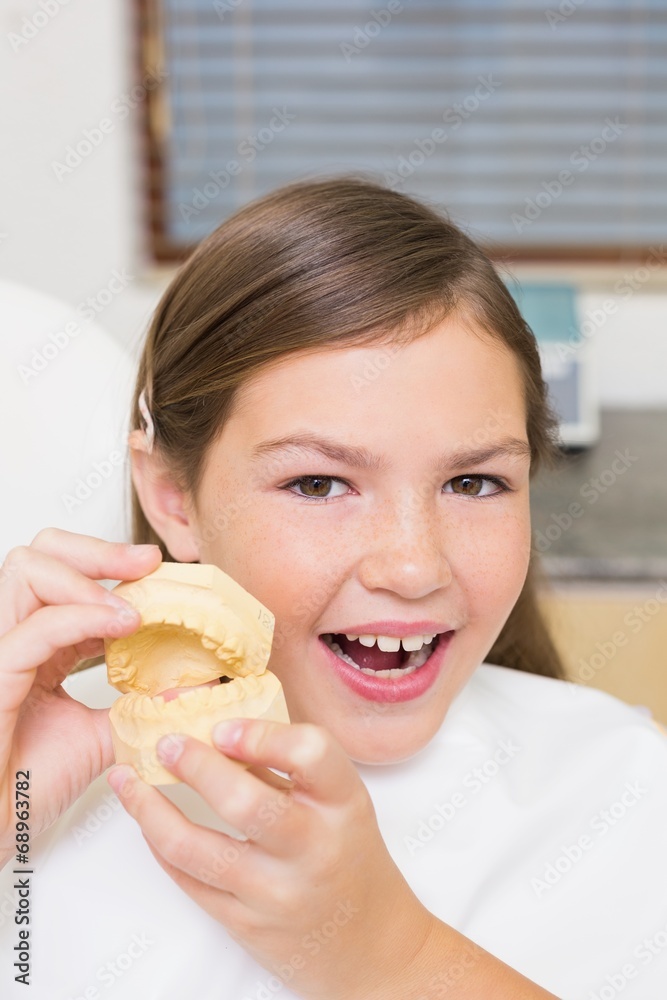 Little girl sitting in dentists chair holding model teeth Little girl sitting in dentists chair holding model teeth