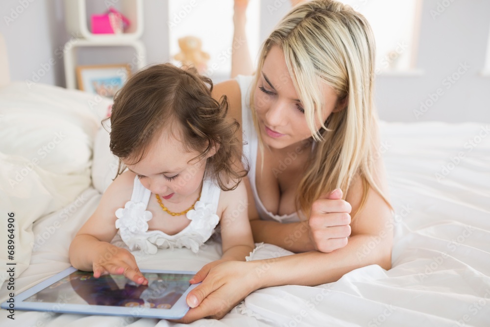 Mother and daughter using digital tablet on bed Mother and daughter using digital tablet on bed