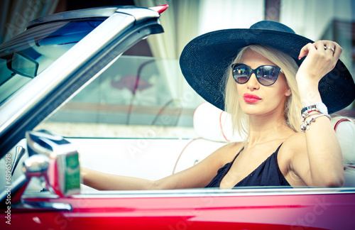Outdoor summer portrait of stylish blonde vintage woman driving 