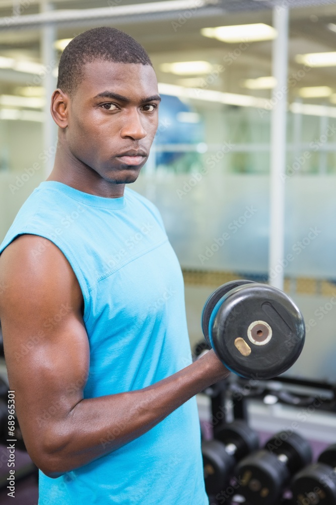 Portrait of young man exercising with dumbbell in gym Portrait of young man exercising with dumbbell in gym