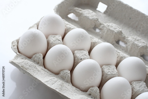 White chicken raw eggs in a box on a white