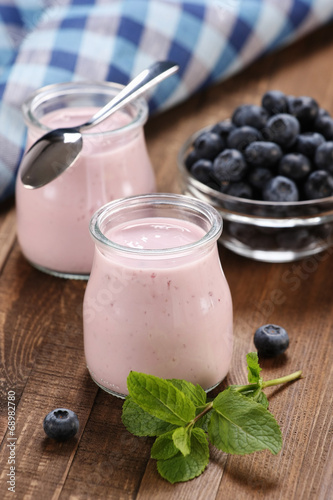 yogurt with blueberries in a glass jar and blueberries in a glas