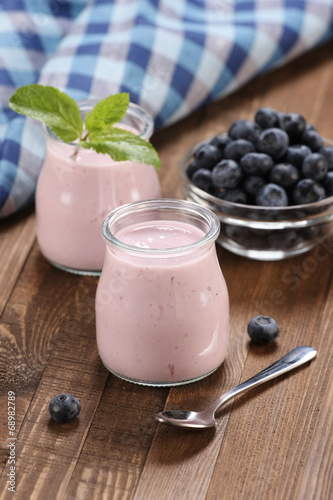 yogurt with blueberries in a glass jar and blueberries in a glas