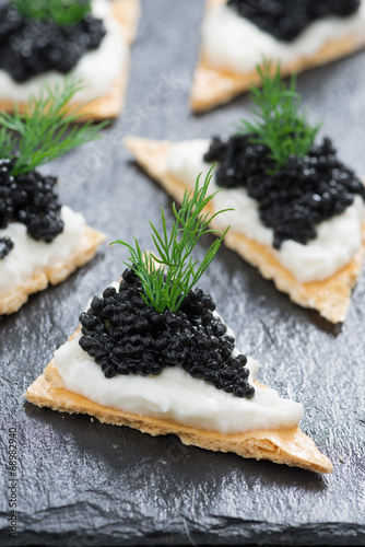 crackers with cream cheese and black caviar, vertical