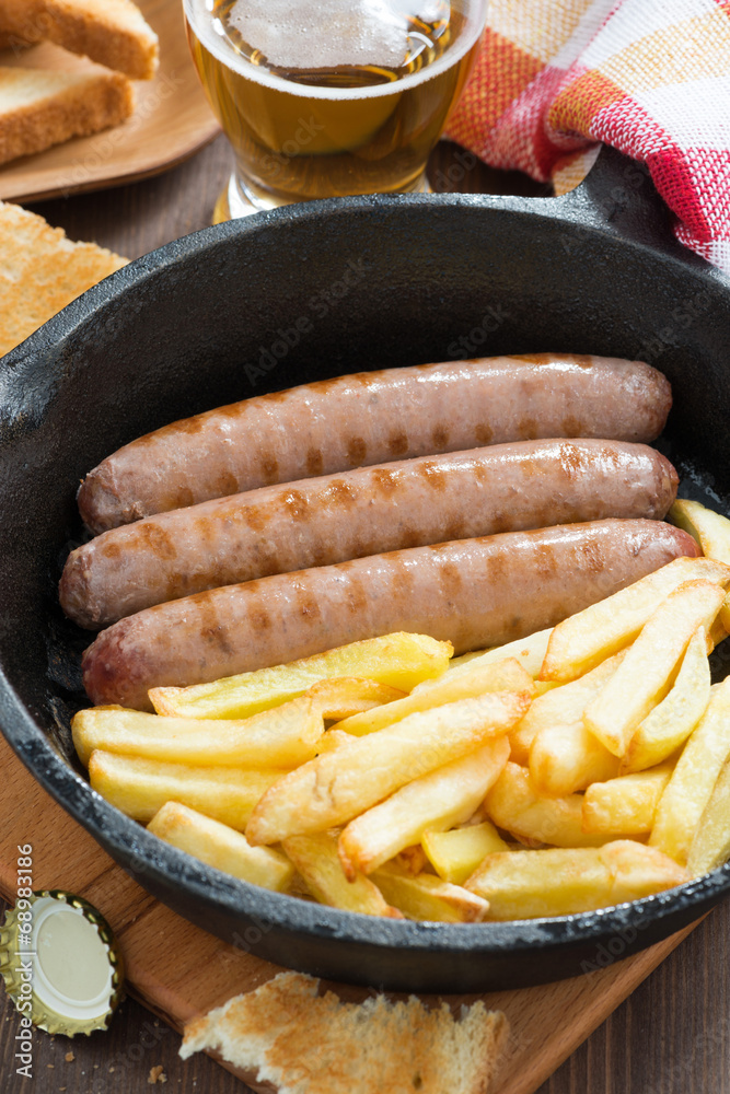 grilled sausages with French fries in a frying pan, vertical grilled sausages with French fries in a frying pan, vertical