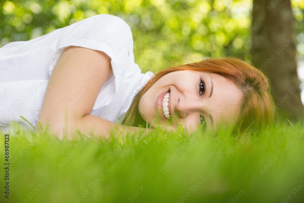 Pretty redhead smiling at camera lying on the grass Pretty redhead smiling at camera lying on the grass