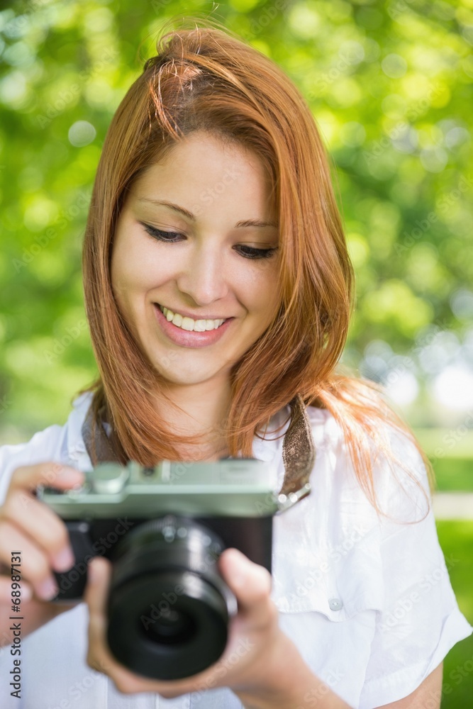 Pretty redhead taking a photo in the park