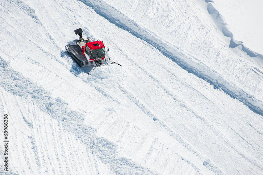 A Tracktor woking on snow field preparing for ski