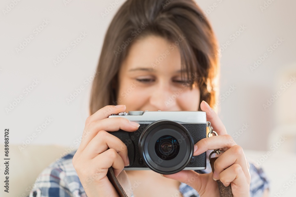 Pretty brunette looking at retro camera on couch Pretty brunette looking at retro camera on couch