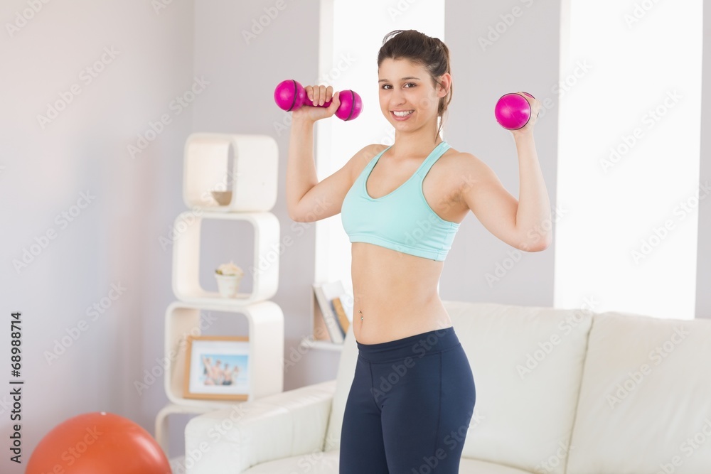 Fit brunette holding dumbbells smiling at camera Fit brunette holding dumbbells smiling at camera