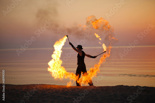 Impressive fire show, torch twirling on the beach