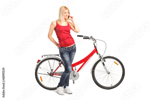 Woman talking on phone and standing by a bike
