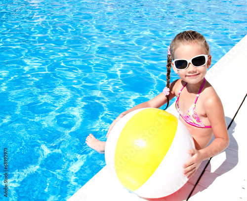Smiling little girl with ball in swimming pool