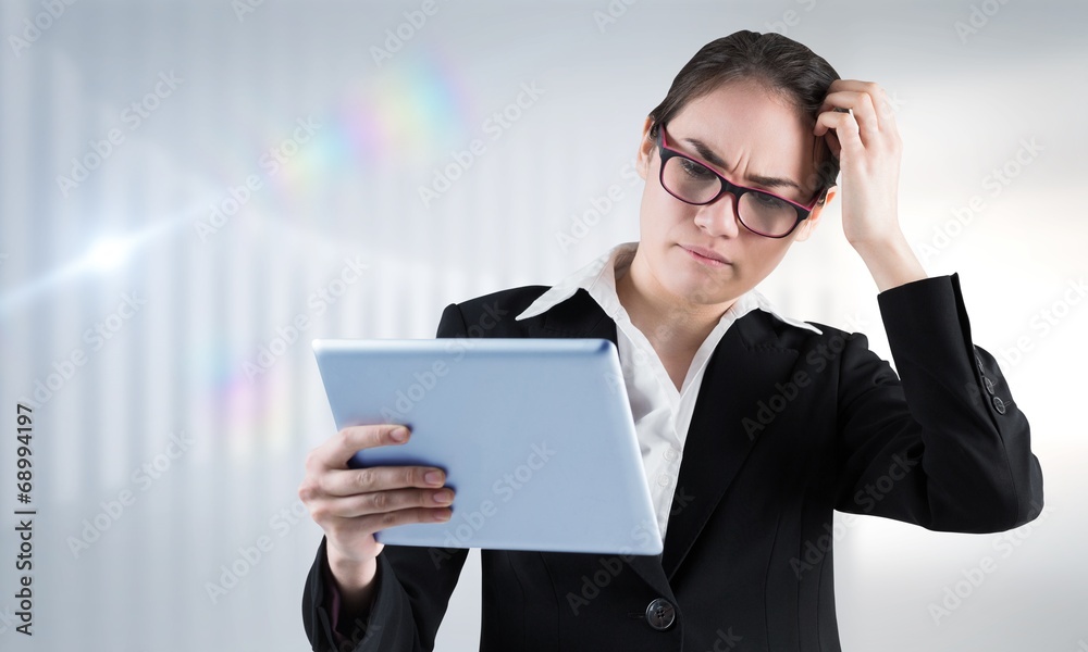 Composite image of thinking businesswoman looking at tablet pc Composite image of thinking businesswoman looking at tablet pc