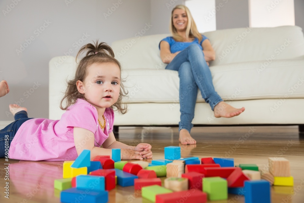 Girl playing with building blocks while mother on conch Girl playing with building blocks while mother on conch