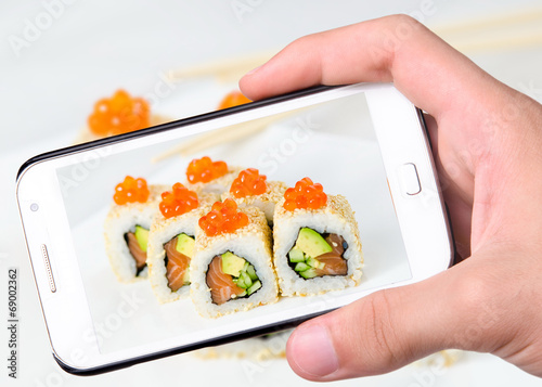 Hands taking photo sushi   with smartphone