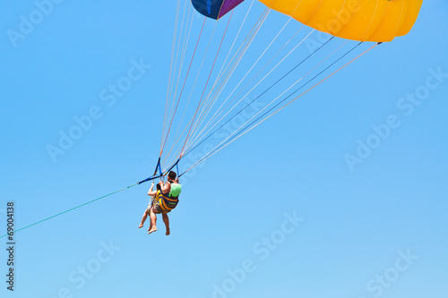 couple people parasailing on parachute in blue sky