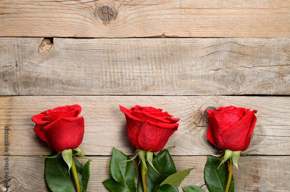 Red roses on wooden background - obrazy, fototapety, plakaty 
