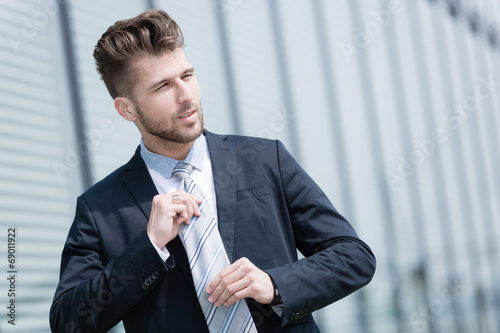 Junger Geschäftsmann bindet Krawatte photo