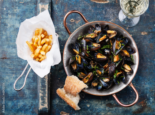 Bild auf Leinwand Mussels in copper cooking dish and french fries on blue backgrou
