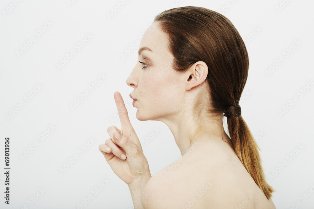 Profile of young woman with finger on lips Profile of young woman with finger on lips