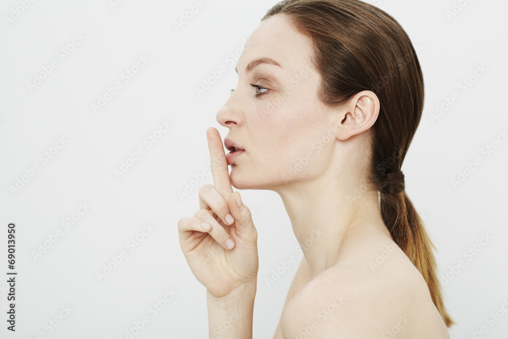 Profile of young woman with finger on lips Profile of young woman with finger on lips