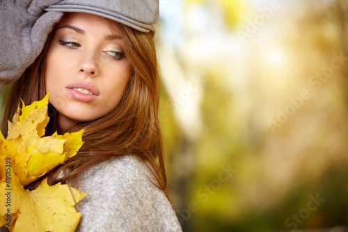 Young woman with autumn leaves in hand and fall yellow maple par