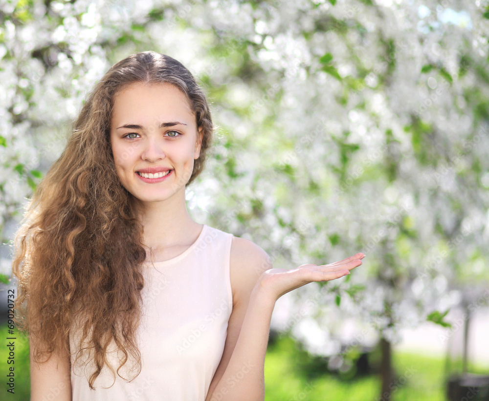 Lovely young curly girl with a charming smile shows a hand gestu Lovely young curly girl with a charming smile shows a hand gestu