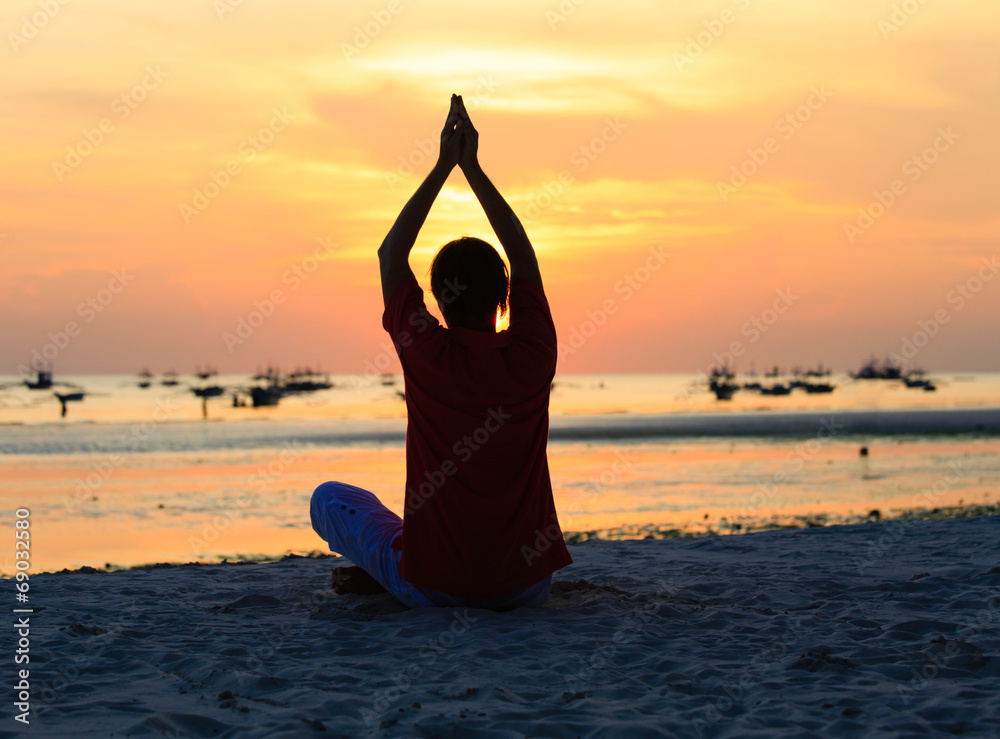 Silhouette of man doing yoga at sunset beach