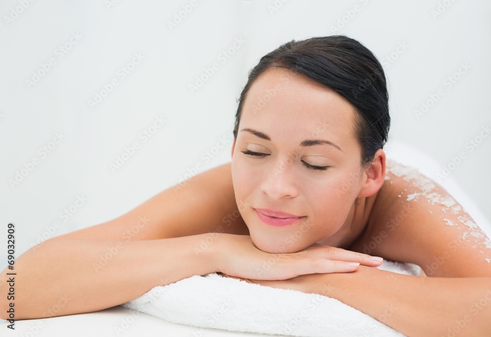 Peaceful brunette lying with salt scrub on back Peaceful brunette lying with salt scrub on back