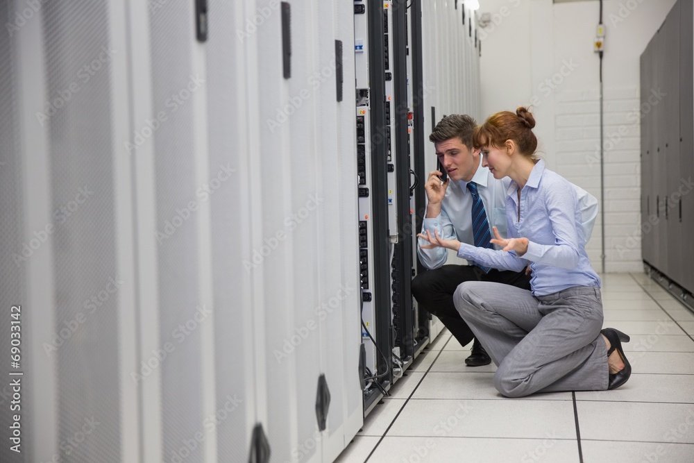 Team of technicians kneeling and looking at servers