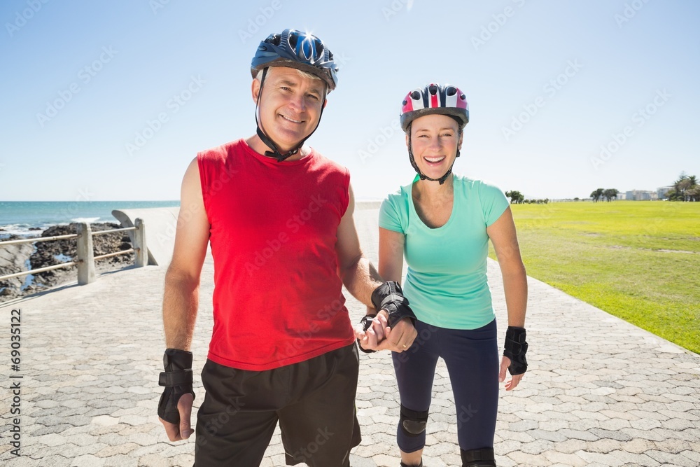 Fototapeta premium Fit mature couple rollerblading on the pier