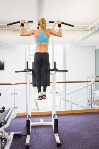 Rear view of fit woman doing pull ups at gym