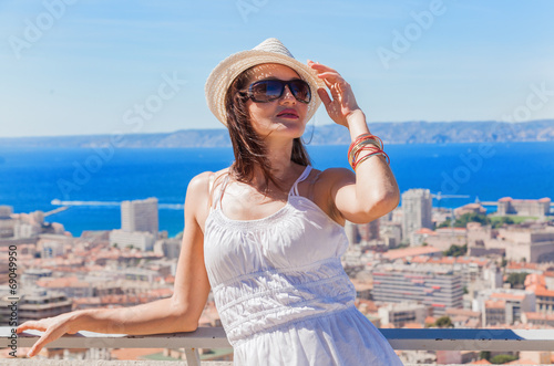Pretty girl in a hat and sunglasses posing against the city of