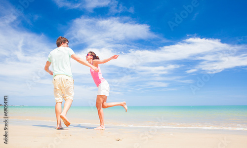 back view of happy young couple running at tropical beach
