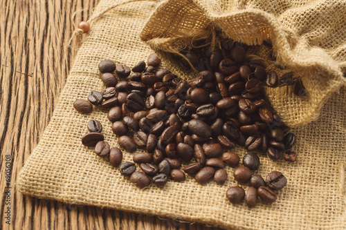 Coffee beans in coffee bag on wooden background © praisaeng