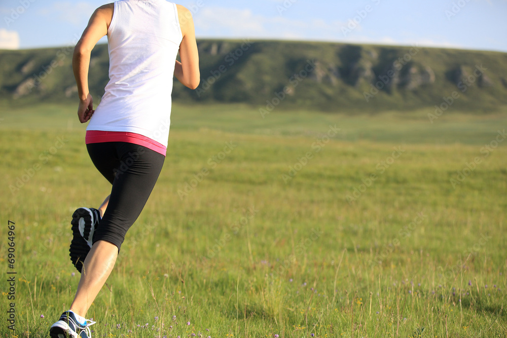Runner athlete legs running on mountain grassland Runner athlete legs running on mountain grassland