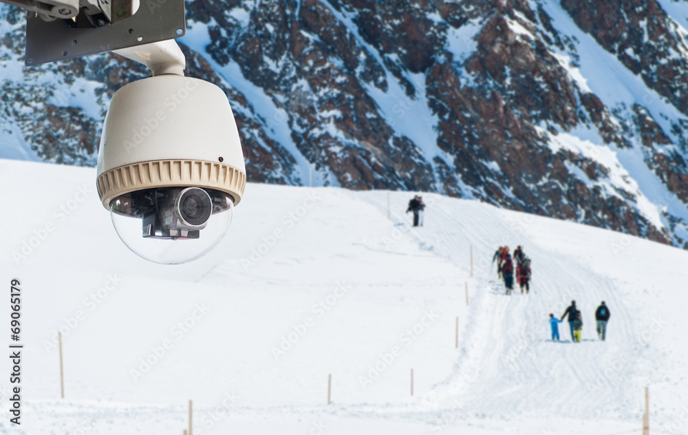 CCTV Camera Operating on snow mountain with people hiking in bac