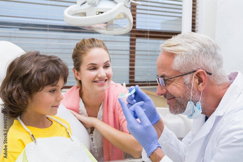 Obraz premium Pediatric dentist showing little boy a toothbrush