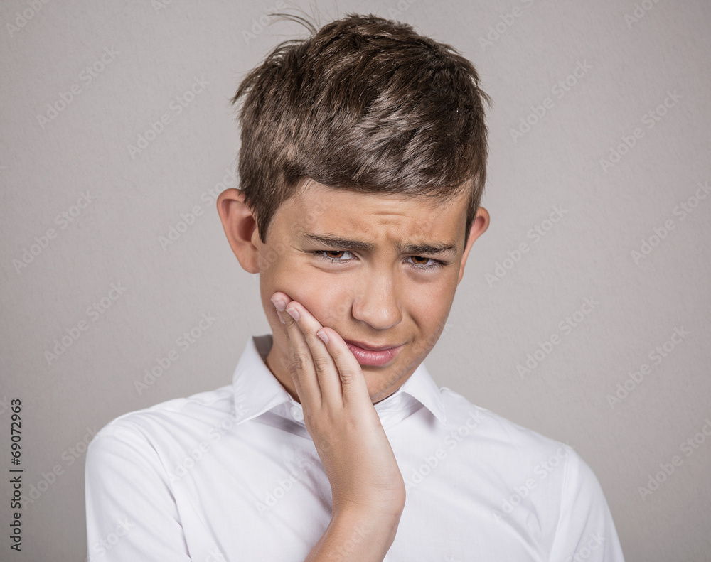 Headshot Unhappy boy with toothache on grey wall background Headshot Unhappy boy with toothache on grey wall background