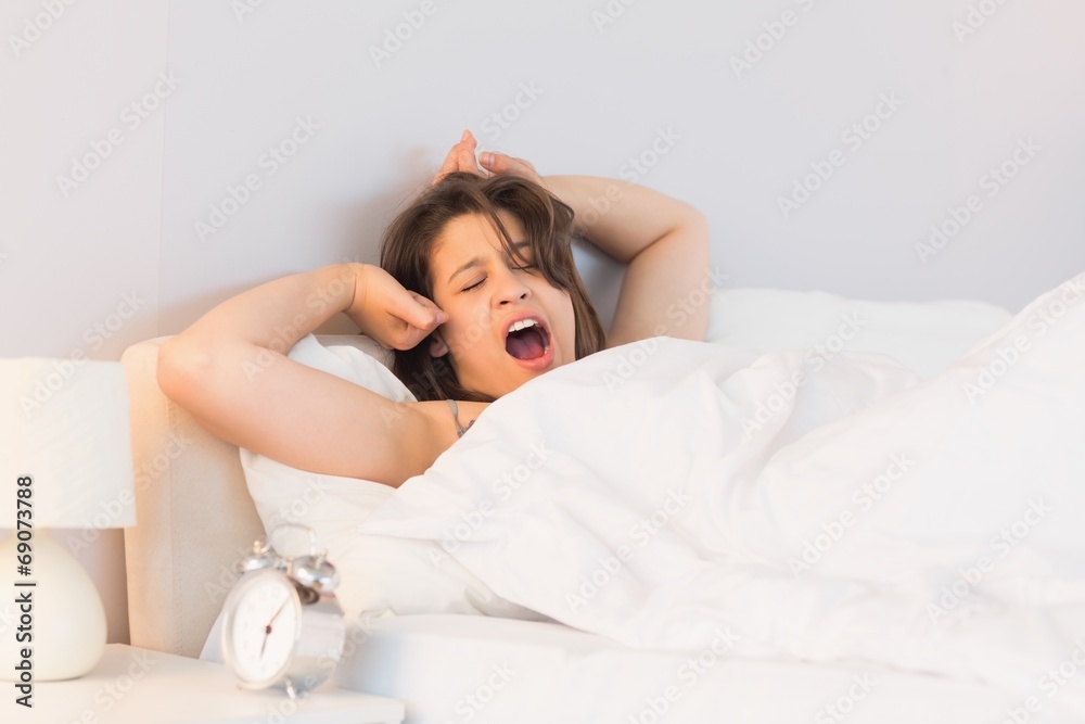 Beautiful brunette yawning and stretching in her bed Beautiful brunette yawning and stretching in her bed