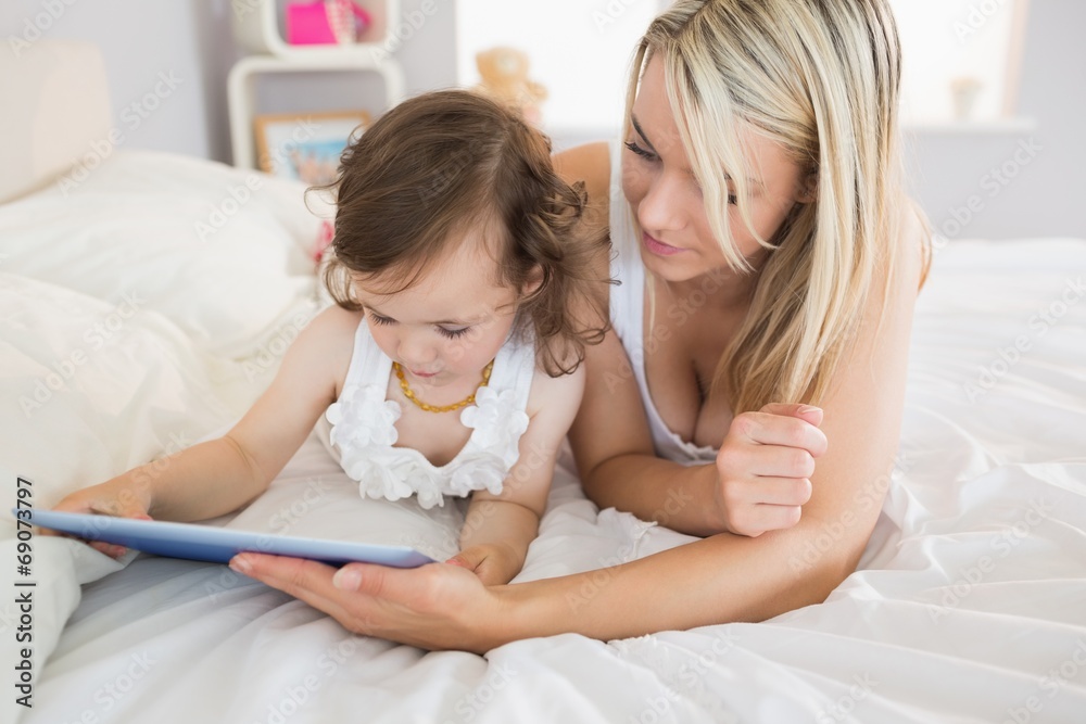 Mother and daughter using digital tablet on bed Mother and daughter using digital tablet on bed